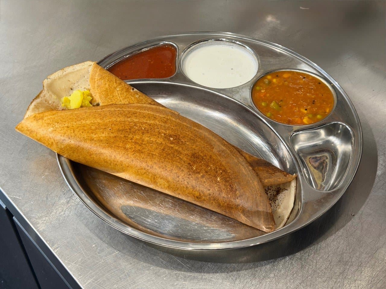 A crisp golden dosa served with sambar, coconut chutney and a small salad